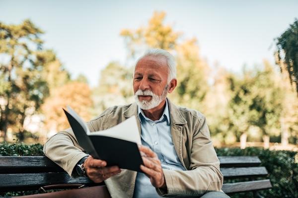 Man smiling and reading a book in the park