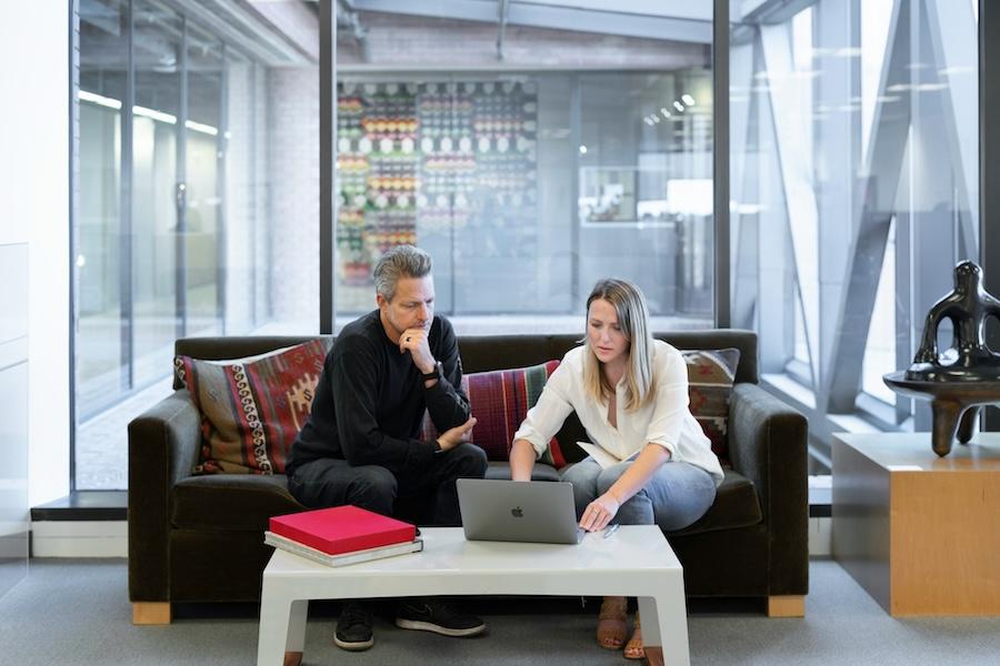 A man and a woman looking at a laptop in a meeting